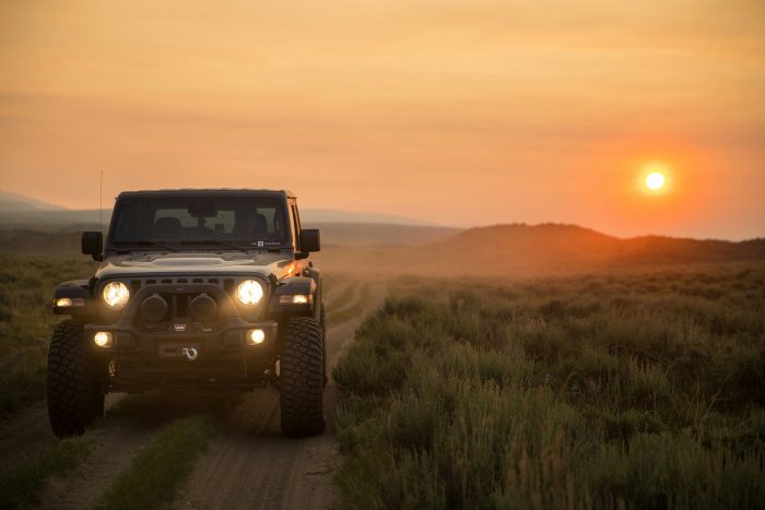 Jeep diving off road with sun setting in background